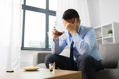 酒精中毒、酒精成瘾与人们的观念--男性酒鬼在家喝白兰地。男性在家中饮酒
