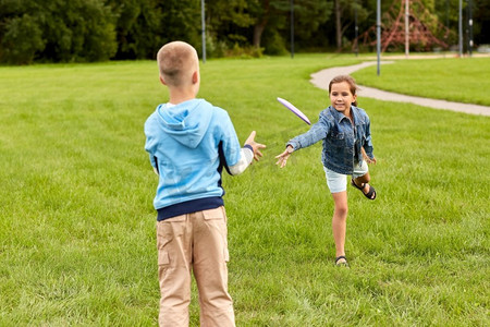童年、休闲和人的概念快乐的孩子们在公园里玩飞盘游戏。快乐的孩子们在公园里玩飞碟