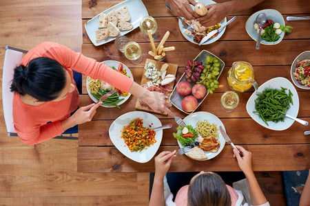 吃喝玩乐的概念--一群人在餐桌上与食物一起用餐。一群人带着食物在餐桌上吃饭