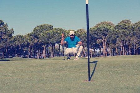 在风和日丽的日子里，高尔夫球手在球场上用球杆瞄准射击。高尔夫球手打出完美的一杆