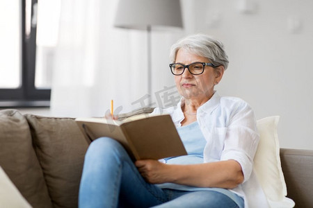 年龄，休闲和人的概念—快乐的高级妇女写笔记本或日记在家里。老年妇女写笔记本或日记在家里