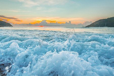 海浪汹涌摄影照片_日落时汹涌的海浪。近距离拍摄日落时海滩上汹涌的海浪，热带风光