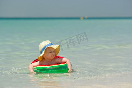 儿童游泳圈摄影照片_海滩上戴着充气游泳圈的两岁幼儿