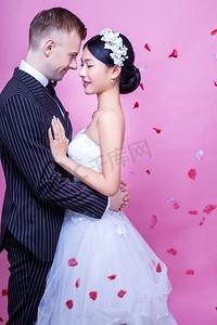 粉色背景下浪漫婚礼情侣拥抱的侧视