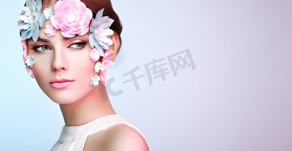 美丽的女人的脸用鲜花装饰。完美的化妆。美丽时尚模特女人面部完美的皮肤。纸花