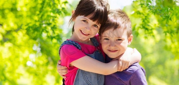 童年、友谊和家庭概念—拥抱在绿色自然背景的两个快乐的孩子愉快的孩子拥抱在绿色自然背景