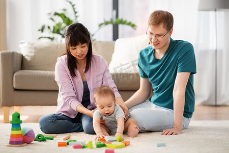 家庭，为人父母和人的概念—快乐的母亲，父亲和婴儿男孩在家里玩玩具块。快乐的家庭与婴儿男孩玩在家里