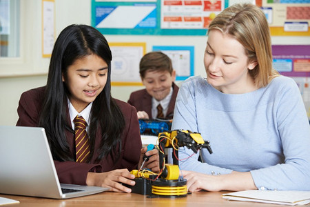 电脑制作摄影照片_在学习机器人的科学课上，老师和女学生在一起