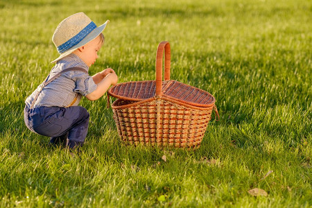 户外蹒跚学步的孩子的肖像。农村场景与一岁大的男婴戴草帽看在野餐篮