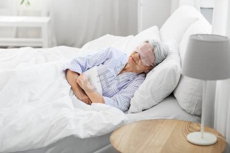 老卧室摄影照片_老年和人的概念—高级妇女与眼罩睡在床上在家里卧室。老年妇女与眼罩睡在床上在家里