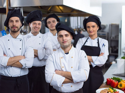 厨卫电器广告摄影照片_在餐厅的商业厨房里，集体厨师站在一起的肖像。群厨画像