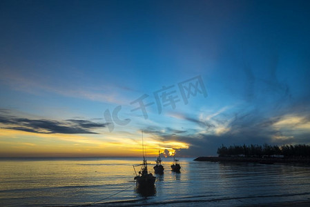 日出时，有船和渔夫的早晨海洋生活