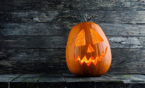 灰色旧木背景上发光的万圣节南瓜头杰克灯笼.南瓜灯吊坠