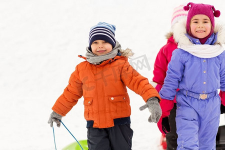 童年，雪橇和季节概念—一群快乐的小孩子在冬天雪橇。快乐的小孩子与雪橇在冬天