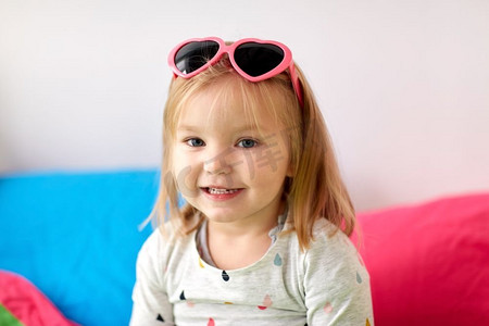 童年与人的概念-戴着心形太阳镜的快乐微笑的小女孩的肖像。戴着墨镜微笑的小女孩的肖像