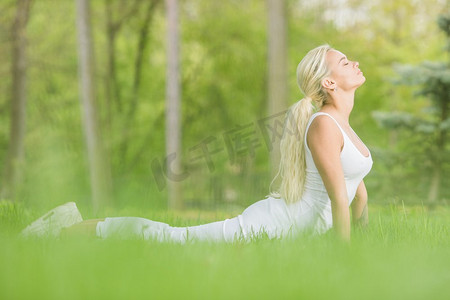 年轻女孩做眼镜蛇瑜伽瑜伽练习在春天公园。年轻的女孩做瑜伽在公园