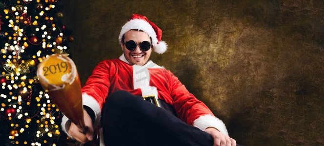 坏圣诞老人与2018年棒球棒坐在圣诞节或新年冷杉树附近的室内。坏圣诞老人与棒球棒