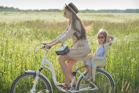 母亲和女儿在大自然中骑自行车。夏季活动