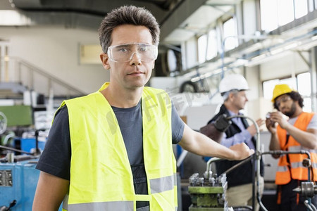 中年工人戴防护眼镜与工业界背景同事合影