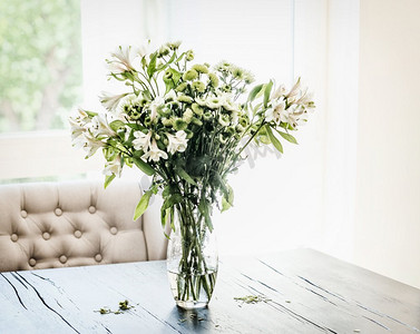 夏天的花束在花瓶上的桌子在客厅的窗口与落花瓣。温馨家居装饰