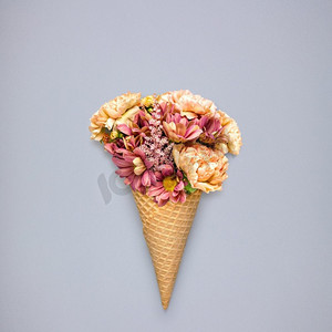 有创意的静物冰淇淋华夫饼蛋卷，灰色背景上有鲜花。