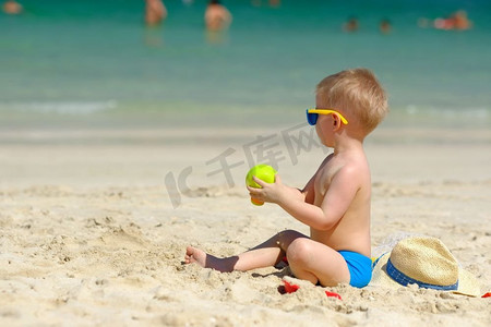 两岁学步男孩在海滩上玩沙滩玩具