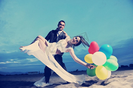 结婚情侣摄影照片_幸福刚刚结婚的年轻夫妇在美丽的日落海滩庆祝和玩乐