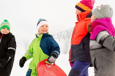 童年，雪橇和季节概念—一群快乐的小孩子在冬天雪橇。快乐的小孩子与雪橇在冬天