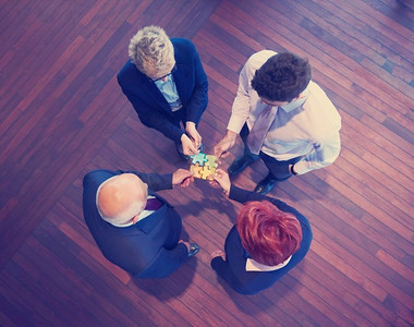商务人士组团拼图，代表团队支持和帮助理念，俯瞰现代明亮的办公室内