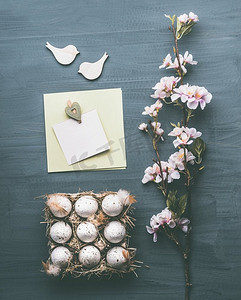 图平铺摄影照片_复活节贺卡布局，由彩蛋、鲜花和空白卡片组成，模拟灰色背景，俯视，平铺