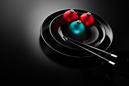 竹盘子摄影照片_一家日本寿司店菜单上的黑色盘子，上面装饰着圣诞球和筷子。