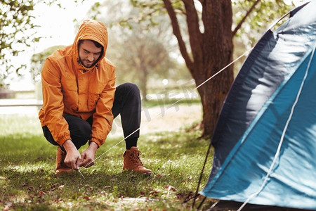 露营、旅游和旅行概念--男人在户外搭帐篷。一名男子在户外搭帐篷