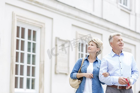 微笑的中年夫妇手挽臂站在大楼外