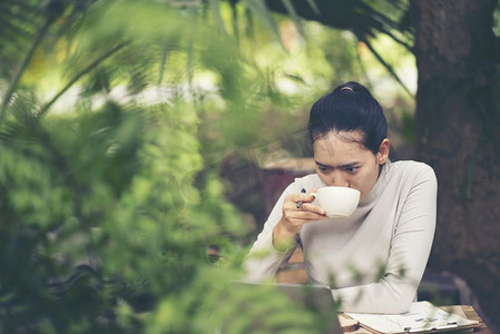 早上咖啡和早餐的概念在户外咖啡馆。一名身份不明的年轻女子的手