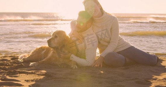 秋日时光摄影照片_一对情侣和一只狗一起在秋日的海滩上享受时光