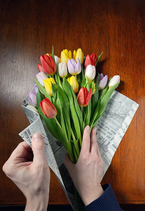 包装康乃馨摄影照片_做郁金香花束，在桌子上用报纸包装