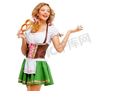 美女服务员摄影照片_啤酒节女服务员穿着传统的巴伐利亚服装，白色背景上孤立着椒盐卷饼的创意概念照片。