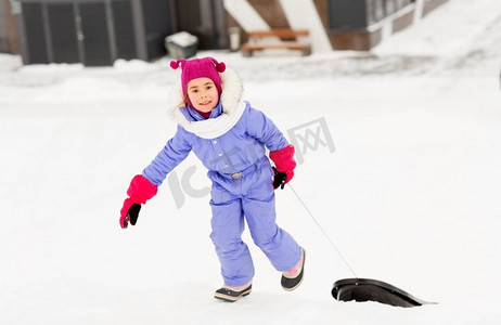 童年，雪橇和季节概念—快乐的小女孩雪橇爬雪山在冬天。小女孩与雪橇在雪山在冬天