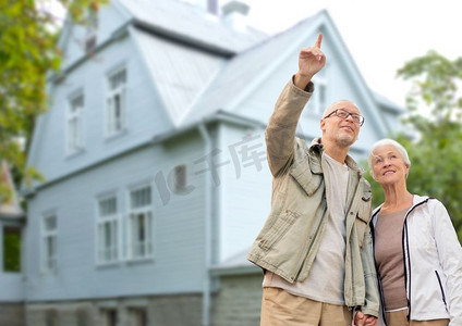 老年，住宿和房地产概念—快乐的老年夫妇超过居住的房子背景。快乐的高级夫妇在生活的房子背景