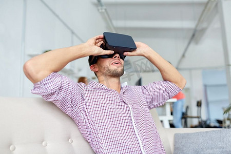 虚拟现实现实摄影照片_技术、增强现实和人们概念快乐的人在办公室戴着虚拟耳机。办公室戴着虚拟现实耳机的快乐男士