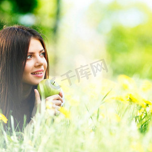 戴着苹果的年轻美女躺在鲜花盛开的青草上