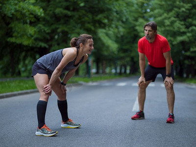 跑步者在晨训前进行热身和伸展运动。健康跑步者团队晨训前在城市公园热身和伸展运动