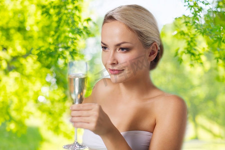 奢华休闲的概念--美丽的女人在水疗中心喝香槟，置身于绿色的自然背景之上。在水疗中心喝香槟的美女
