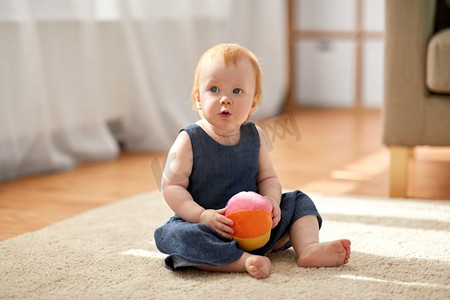 童年，孩子和人的概念—可爱的红头发女婴与玩具球在家里。可爱的红发女郎与玩具球在家里