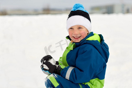 孩子玩雪摄影照片_童年，休闲，季节概念-快乐的小男孩在冬天玩雪。快乐的小男孩在冬天玩雪
