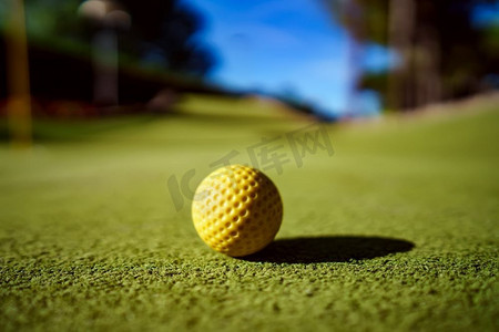 日落时分，绿色草地上的迷你高尔夫黄球