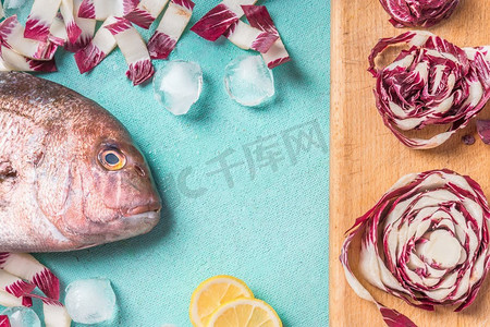 浅蓝色片头摄影照片_生鱼头与烹调成分在浅蓝色厨房桌子背景，顶视图，平的铺设海鲜概念与复制空间