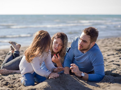 秋日，一家人带着小女儿在海滩上休息和玩耍。年轻的家庭在秋日里享受矢量