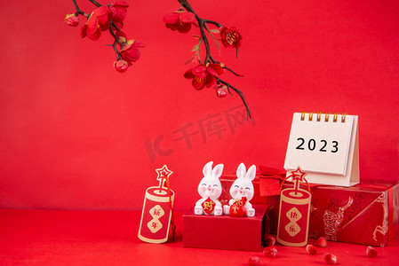 ppt模板红色摄影照片_新年2023台历兔子摆件红色背景摆放兔年