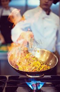 厨师在餐厅的厨房里烹饪和制作食物的火焰。厨师在食物上做火焰弹